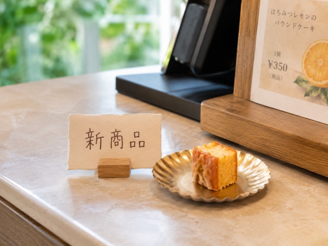 レジ横に置かれた一口サイズのパウンドケーキの試食と「新商品」と書かれたPOP