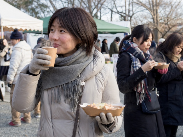 冬イベント会場で飲み物を持ちながら食べ歩きをする来場者の様子